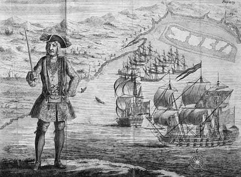 A copper engraving of the pirate captain Bartholomew Roberts standing on a shore in coat and hat with pistols slung across his chest; behind him two ships lie under shortened sail in an open road.