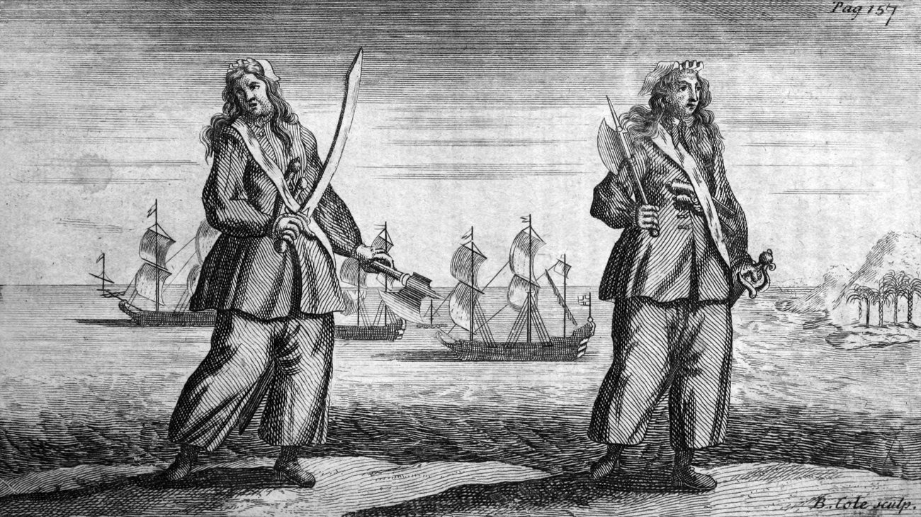 Engraved plate showing two women standing on a shore, each in a jacket and long loose trousers, long hair falling over their shoulders. The figure on the left holds a drawn sword in one hand and an axe in the other; the figure on the right carries an axe over her shoulder and a sword at her side. Anchored sailing ships lie on the water behind them, the corner is marked Pag 157, and the engraver's signature B. Cole sculp sits at the foot.
